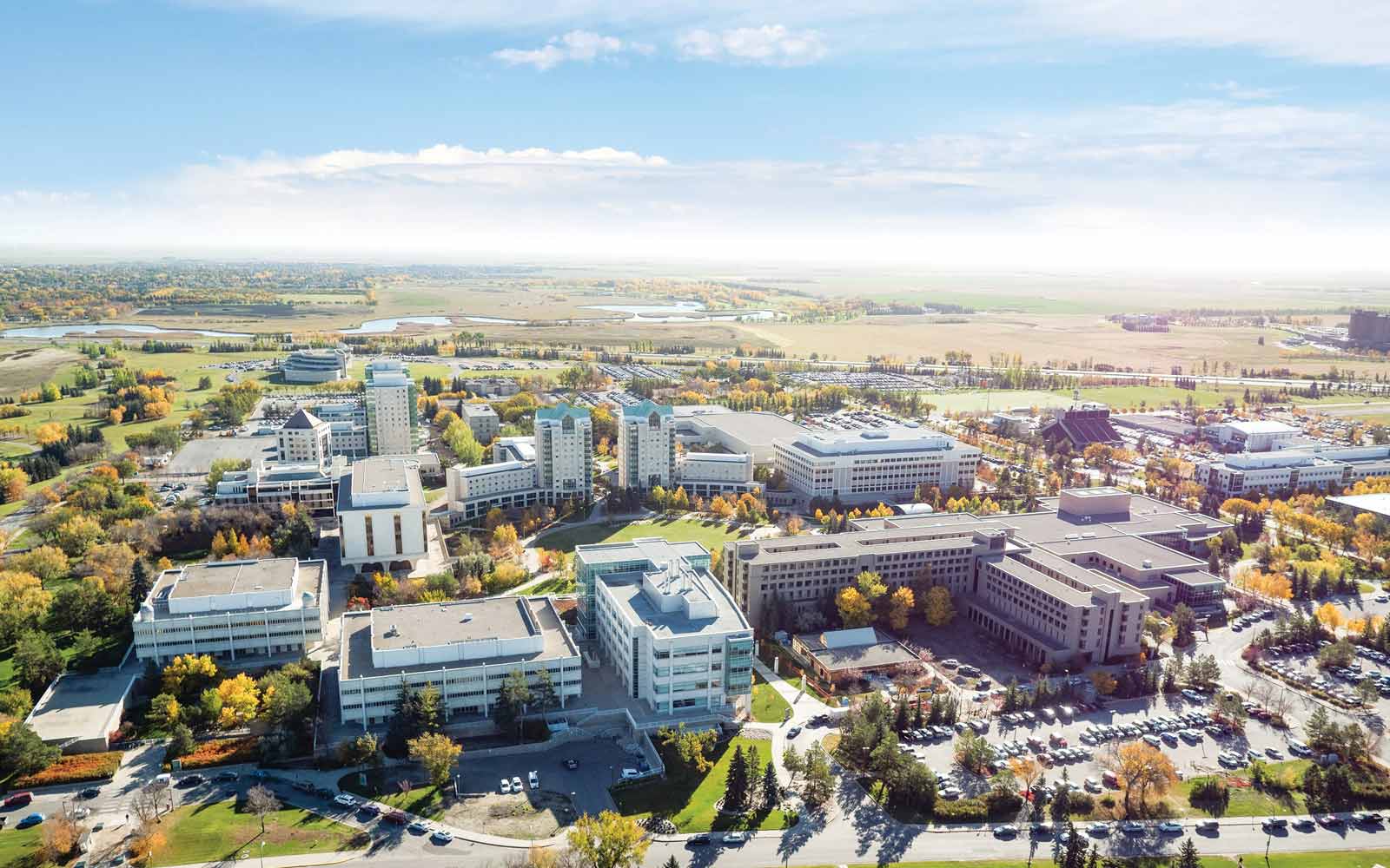 Aerial view of University of Regina campus, with modern buildings surrounded by green space and fields.