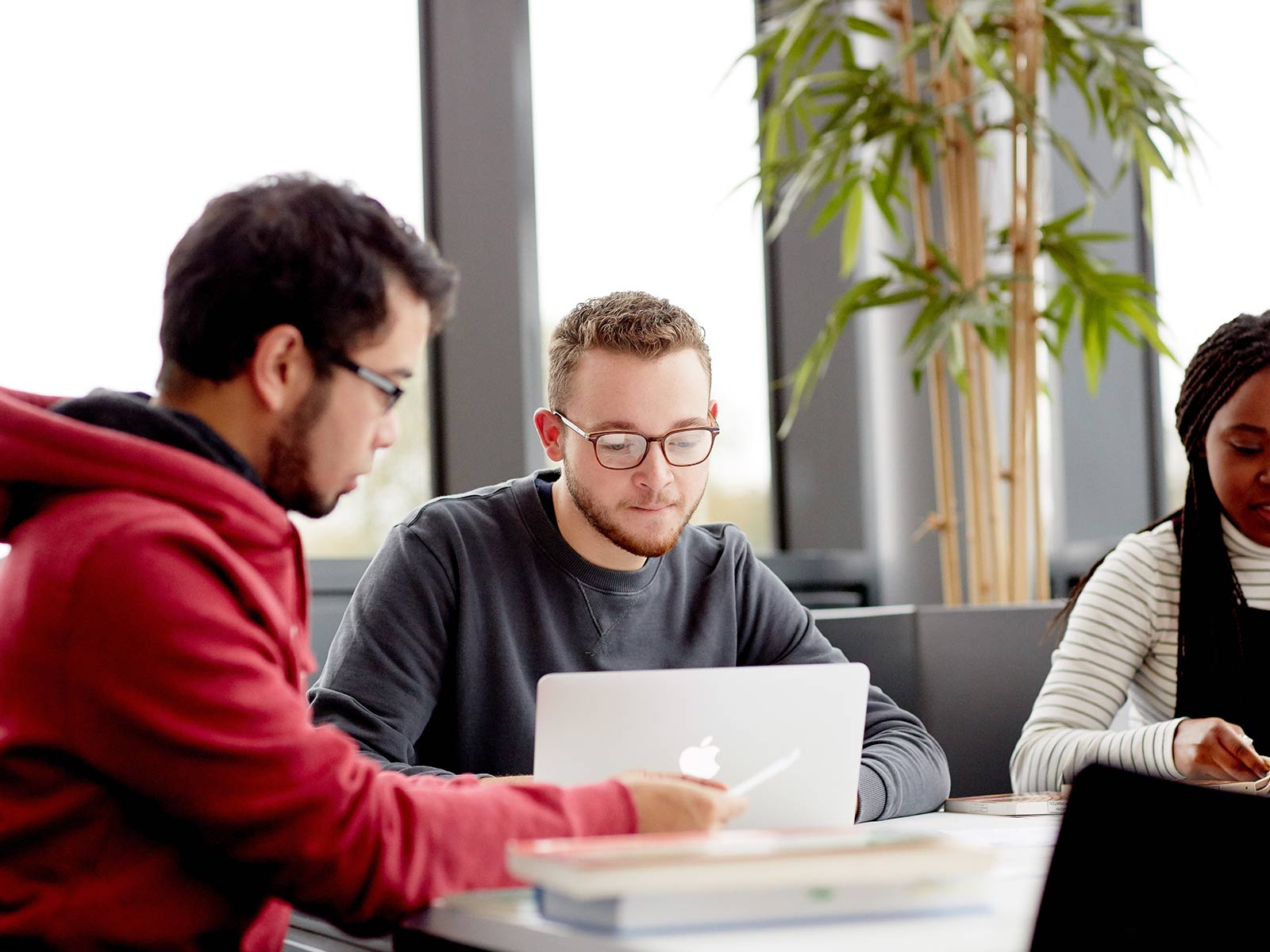 three students working in the library with laptops