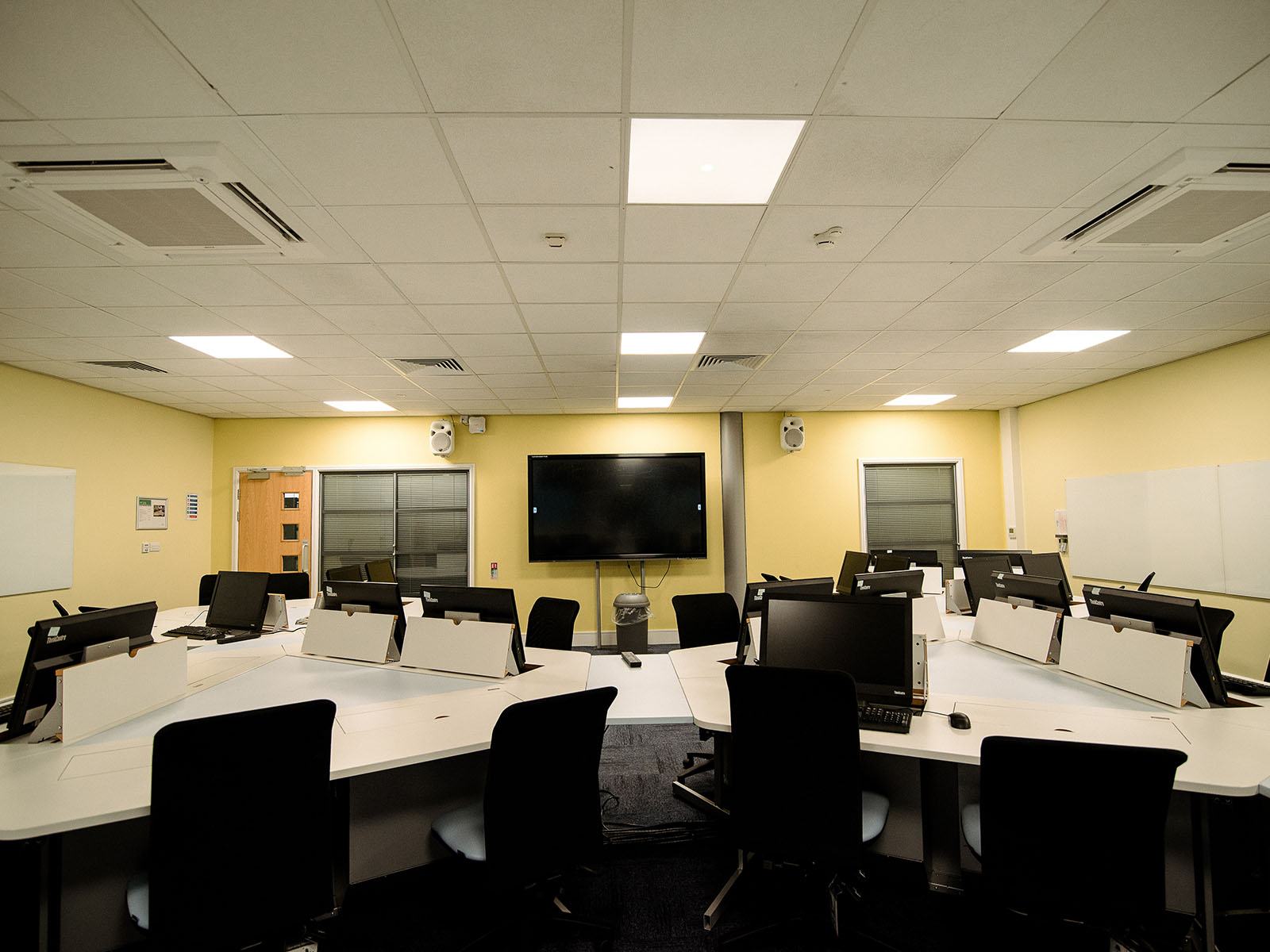 An IT suite with a lectern, presentation screens, and retractable desktop computers