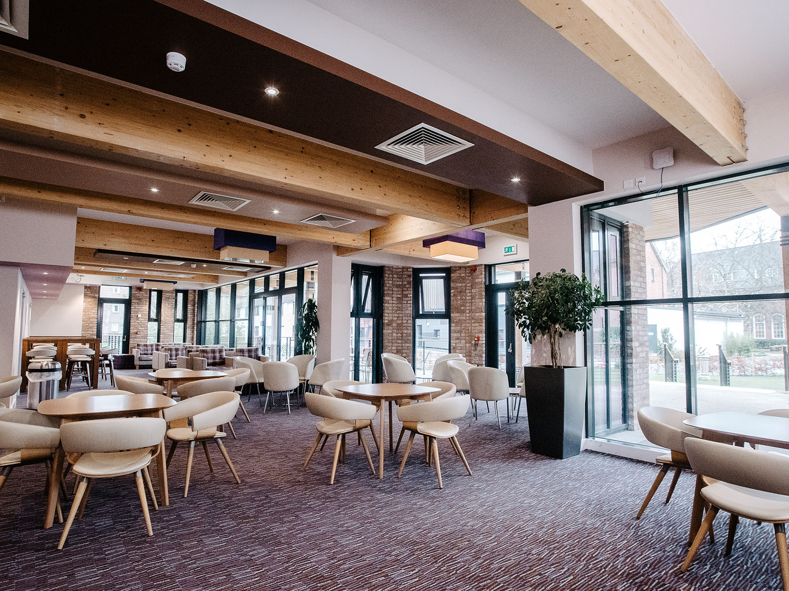 A dining space with seating at tables, stools at bars, and sofas with coffee tables