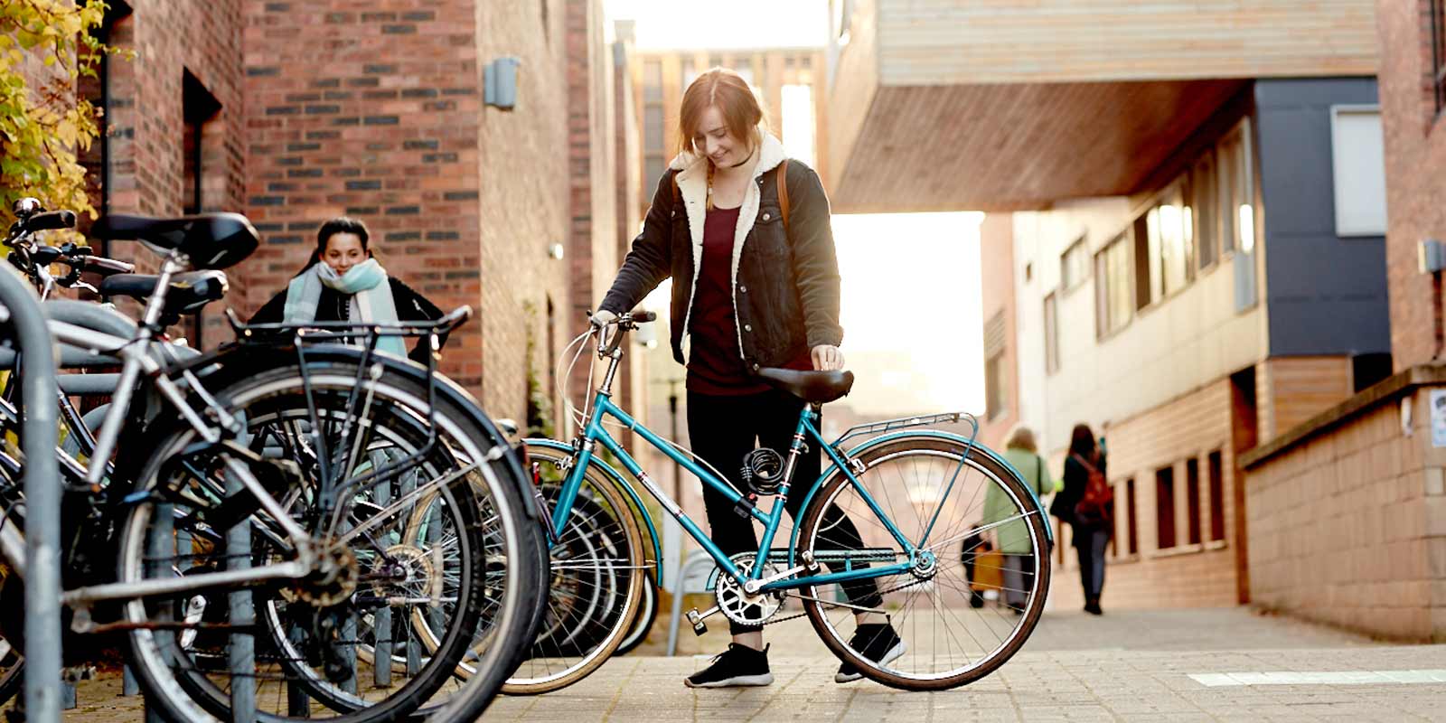 A student parking a bicycle on campus.