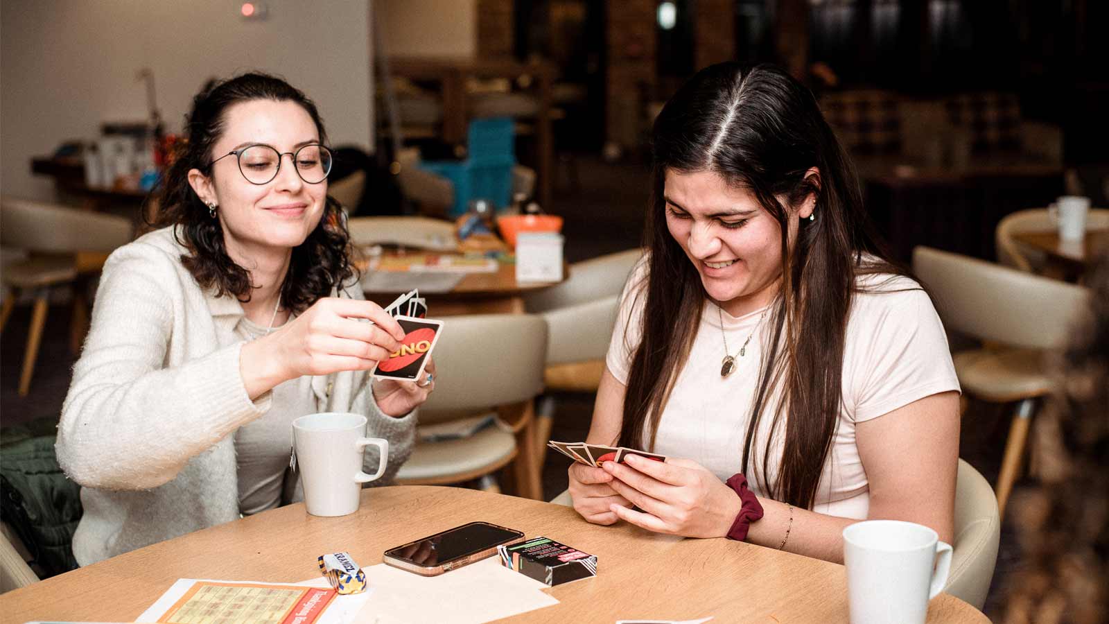 Two students laugh while playing a card game together.