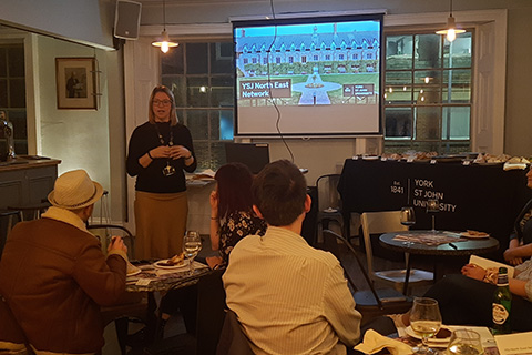 Staff member giving talk in front of screen at North East Alumni Network