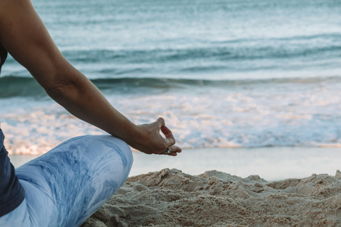 Individual sitting on a beach meditating