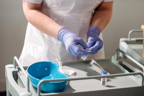 Nurse wearing gloves preparing a syringe in the clinic