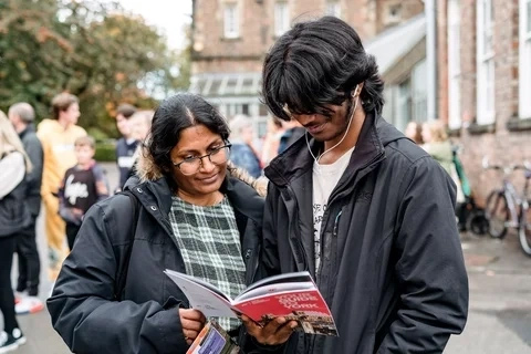 A student and their family member look at an Open Day guide.