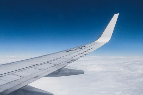 Wing of plane, visible from window, flying over clouds. Photo by Varun Gaba on Unsplash.