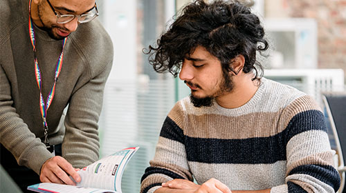 Staff member helping student, showing them brochure