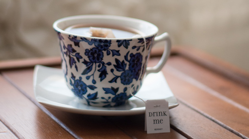 Cup of tea on table with teabag that has drink me label
