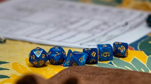 A variety of dice on a game table for Dungeons and Dragons. Photo by Gian-Luca Riner on Unsplash.