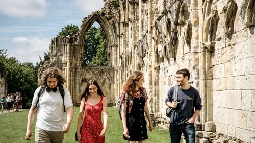 Four students walk together in York Museum Gardens
