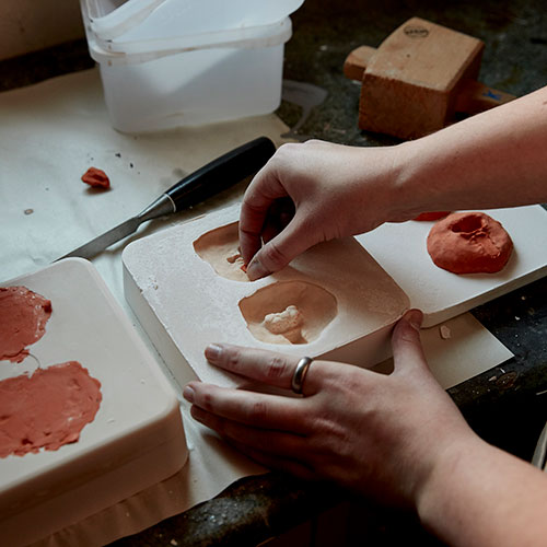Student pressing clay into mould