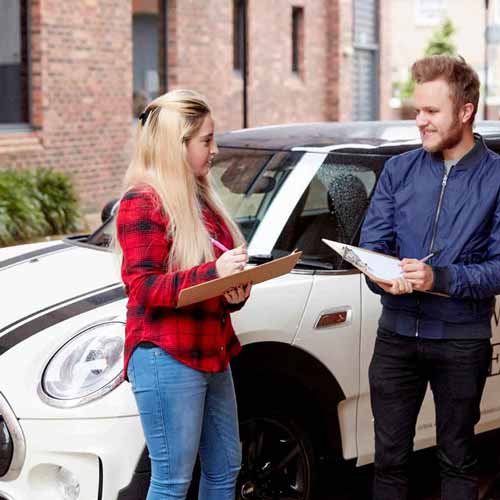 Business students next to car with clipboards