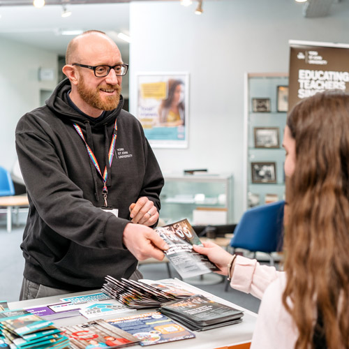 Staff member handing out leaflets to students at Careers Fair