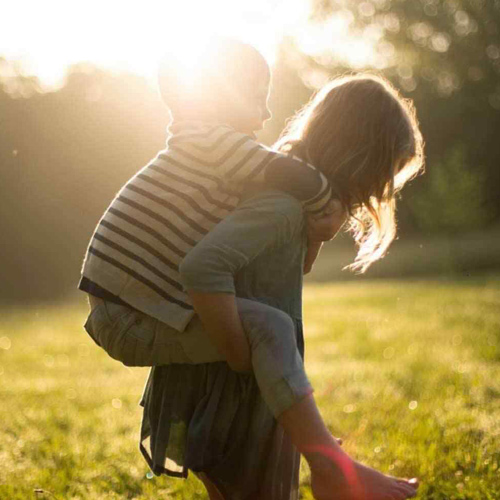 Two children play together in a field.