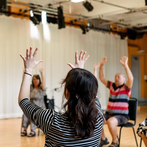 Participants lifting arms in the air during workshop