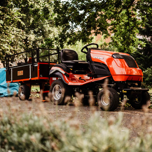 A red garden vehicle surrounded by leafy trees and bushes