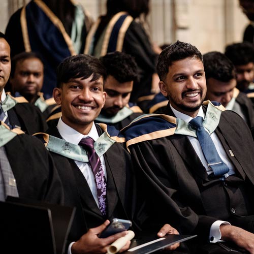 Two students smiling at their graduation ceremony.