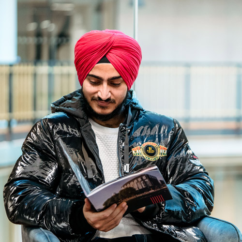 Student sat in chair reading brochure