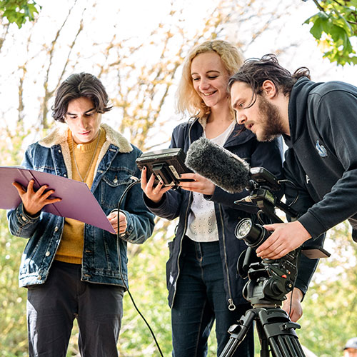 Group of film students using camera equipment outside