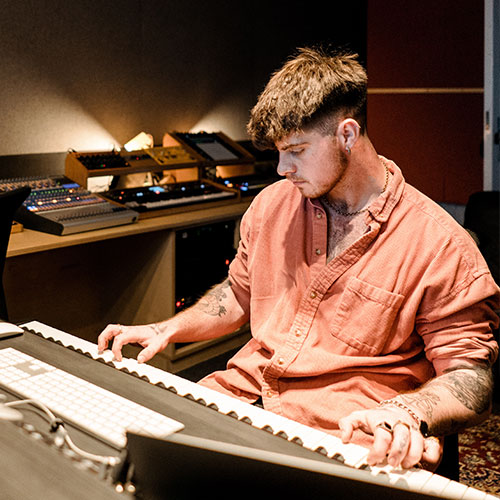 Student playing and recording on a keyboard in the studio