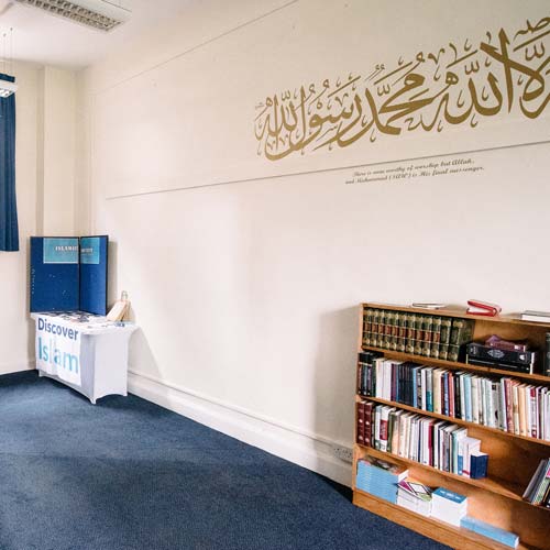 Bookshelf and script on wall in Muslim prayer room