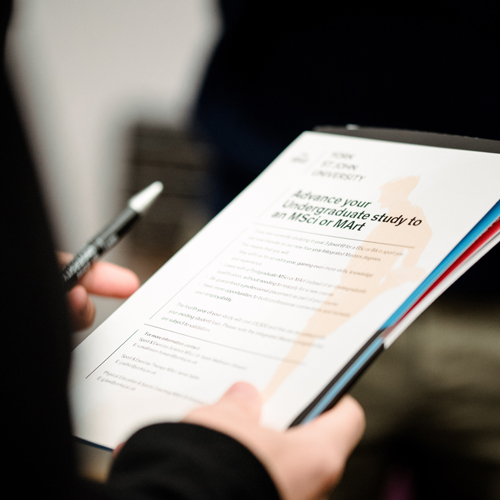 Student looking at clipboard at postgraduate open evening