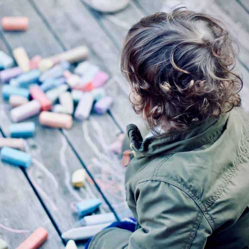 Child drawing with chalks on floor