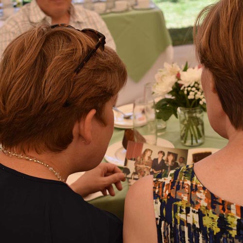 Alumni looking at an old photo at a reunion afternoon tea