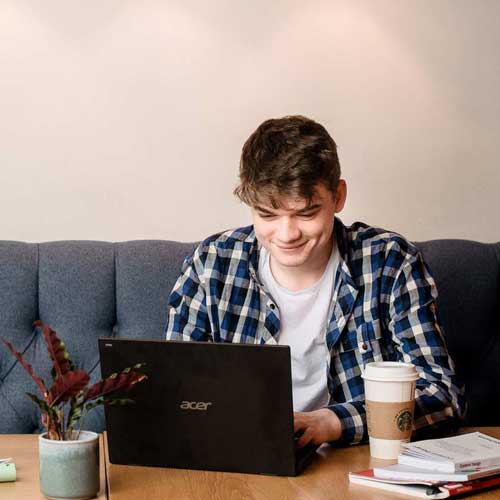 Student on laptop on sofa and coffee table in Students union