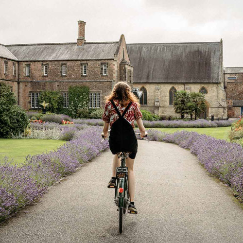 Student cycling down path towards York St John