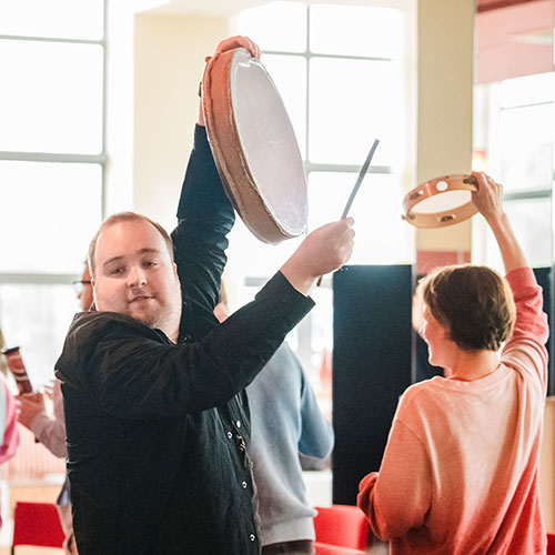 Participants walking playing percussion instruments in I'm Me workshop