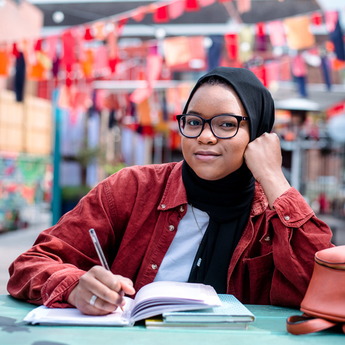 Student writing in notebook at table