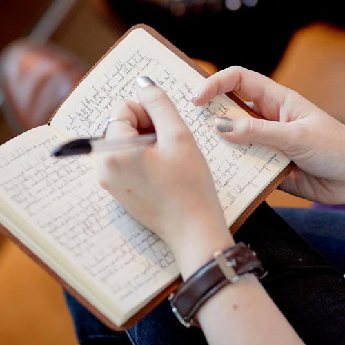 Student writing in notebook in lecture