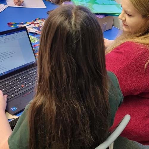 Pupil and adult looking at laptop screen