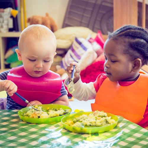 2 young children sat at the table eating 