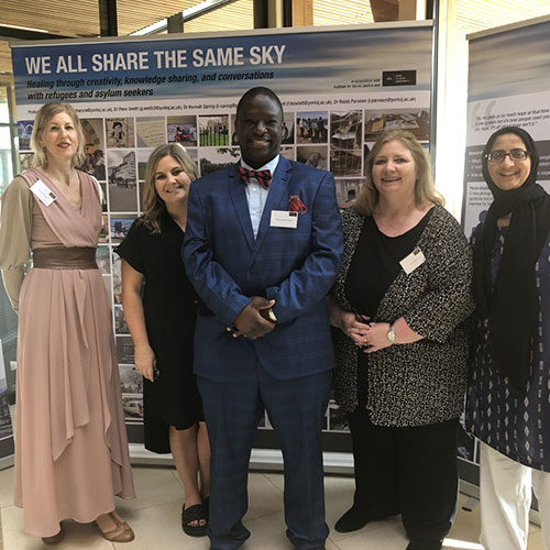 Professor Divine Charura and a group of people in front of 'We all share the same sky' stand