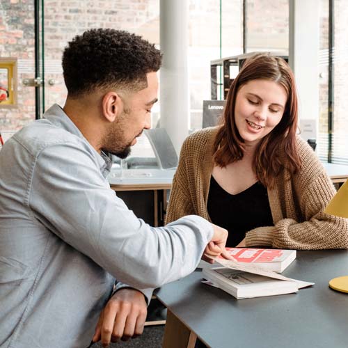 Careers Adviser talking to student, looking at book
