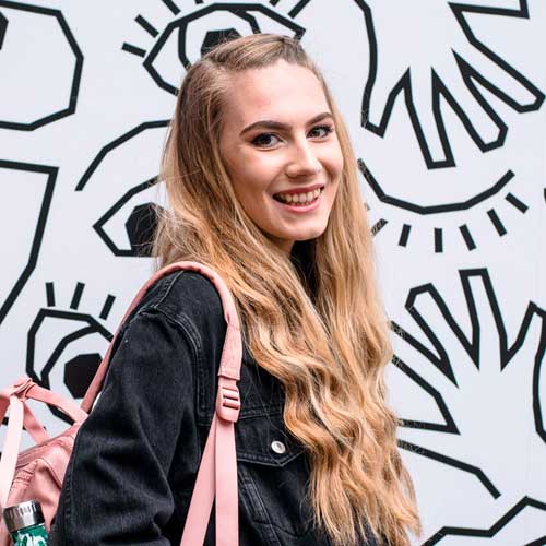 Young undergraduate girl with blonde hair with an mural background