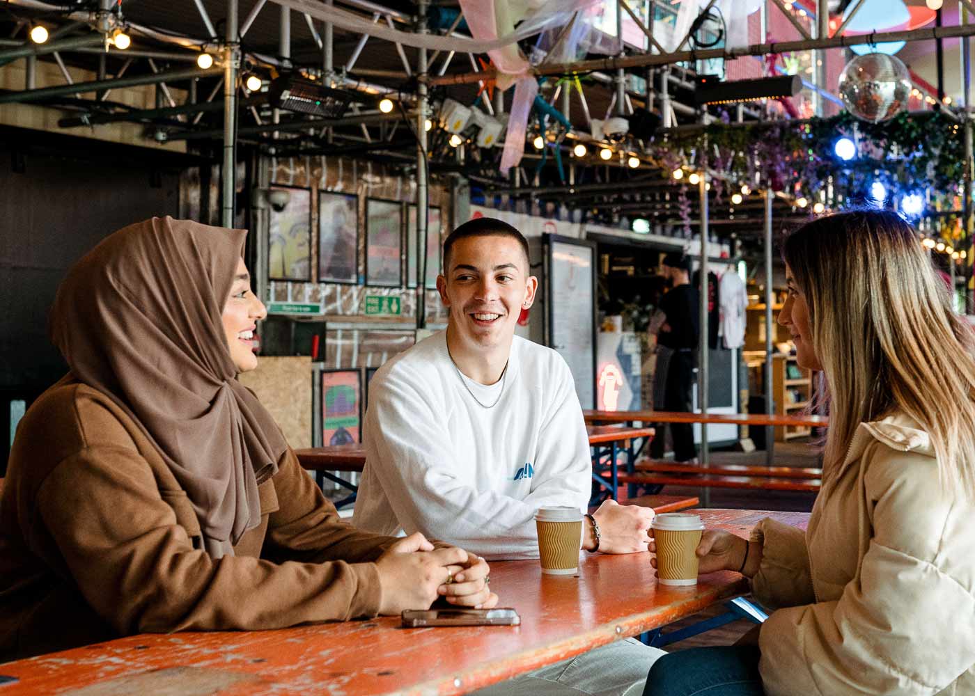 Three students sit and chat in Spark York.