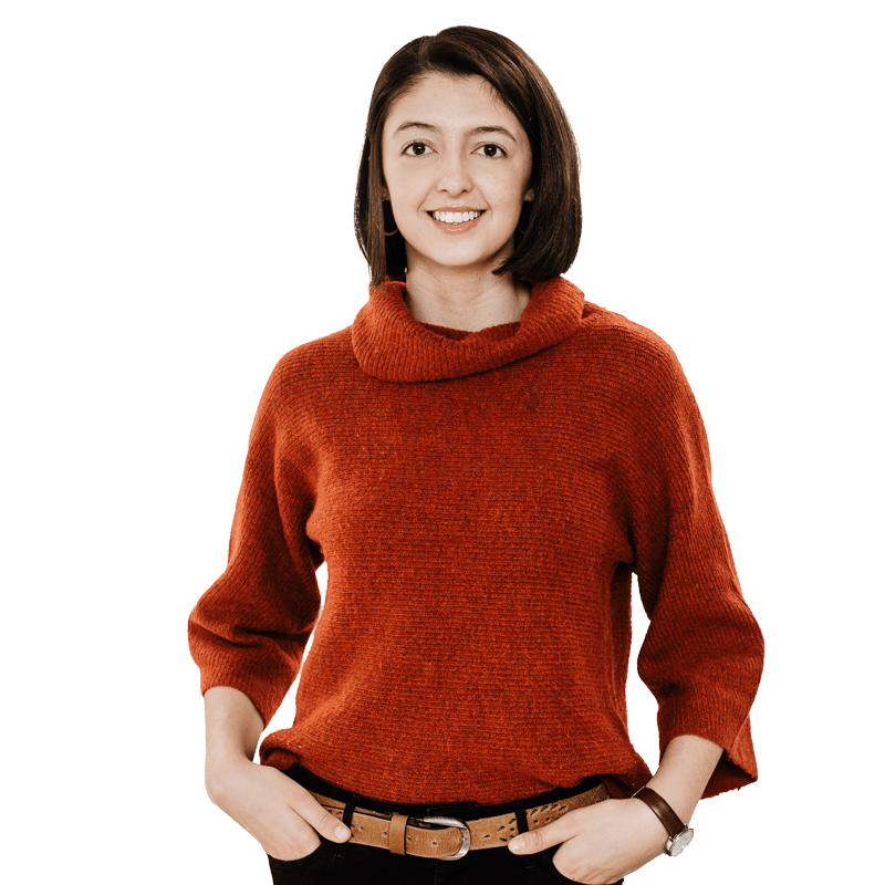 Brunette female student wearing red jumper, smiling at camera, hands on her hips