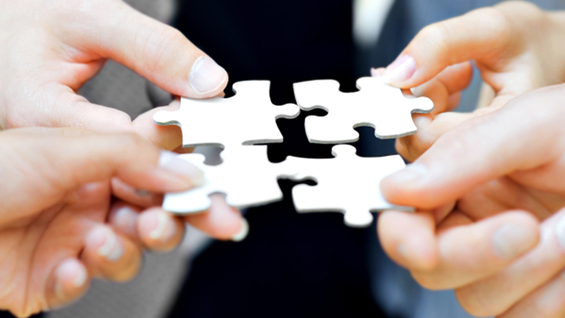 People holding jigsaw pieces together