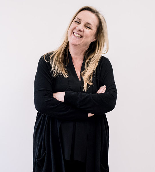 Carol Cloughton smiling and standing with arms crossed