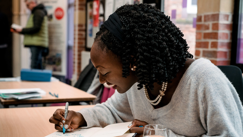 Women sat at desk and writing in a book