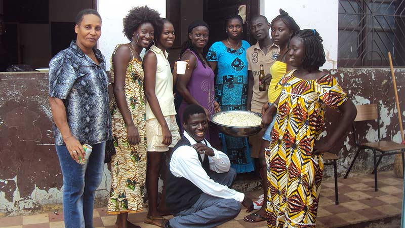 African women standing outside a house. A man is kneeling