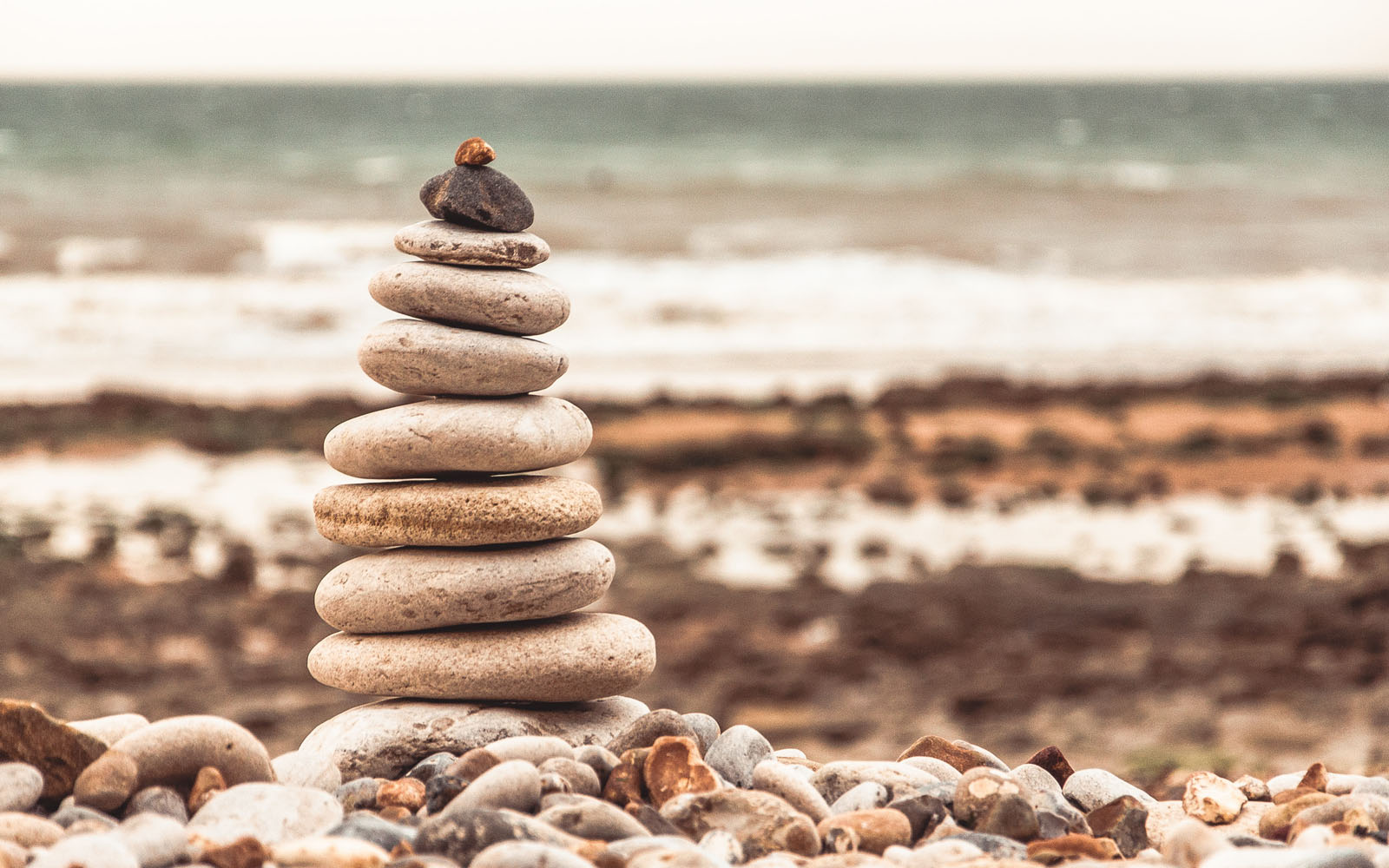 Tower of pebbles on a beach with the sea in the background